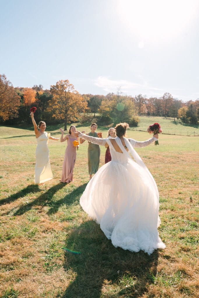 bride runs towards her bridesmaids with open arms at Sassafras Springs Vineyard and Winery