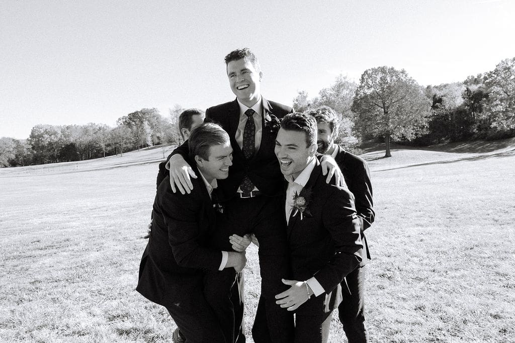 groomsmen lifting up groom while laughing at Sassafras Springs Vineyard and Winery