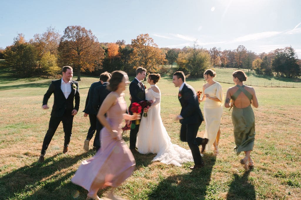 bridesmaids and groomsmen run around bride and groom