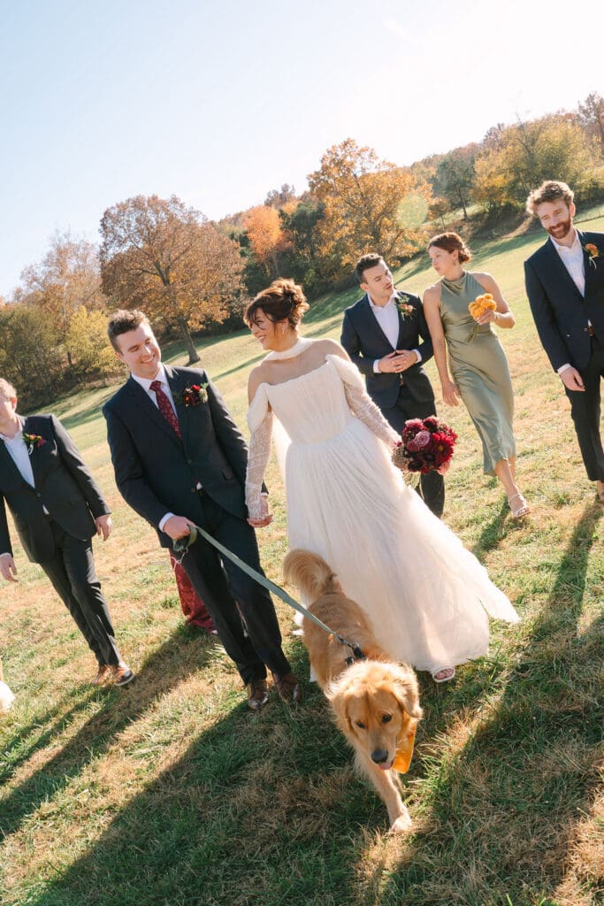 bride and groom walk their dog with bridesmaids and groomsmen