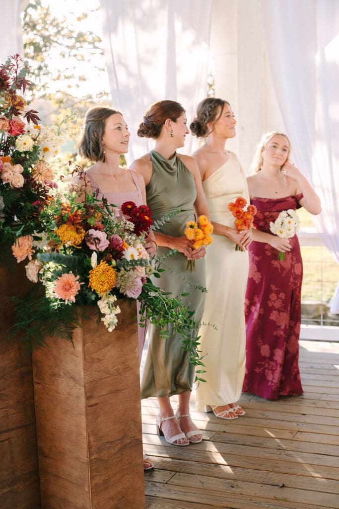 colorful fall colored bridesmaid dresses during ceremony at Sassafras Springs Vineyard and Winery