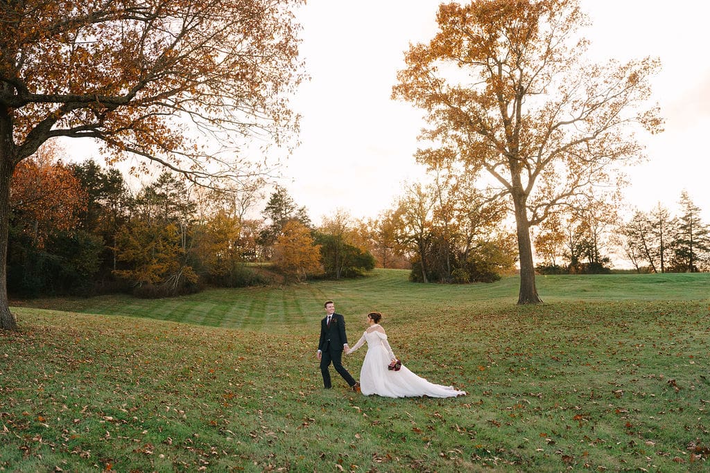 wide shot of bride and groom walking holding hands at Sassafras Springs Vineyard and Winery during golden hour