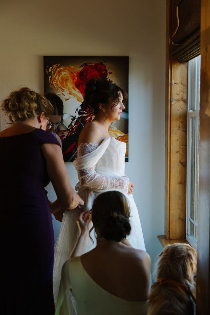 Bride gets ready with mom zipping her into dress